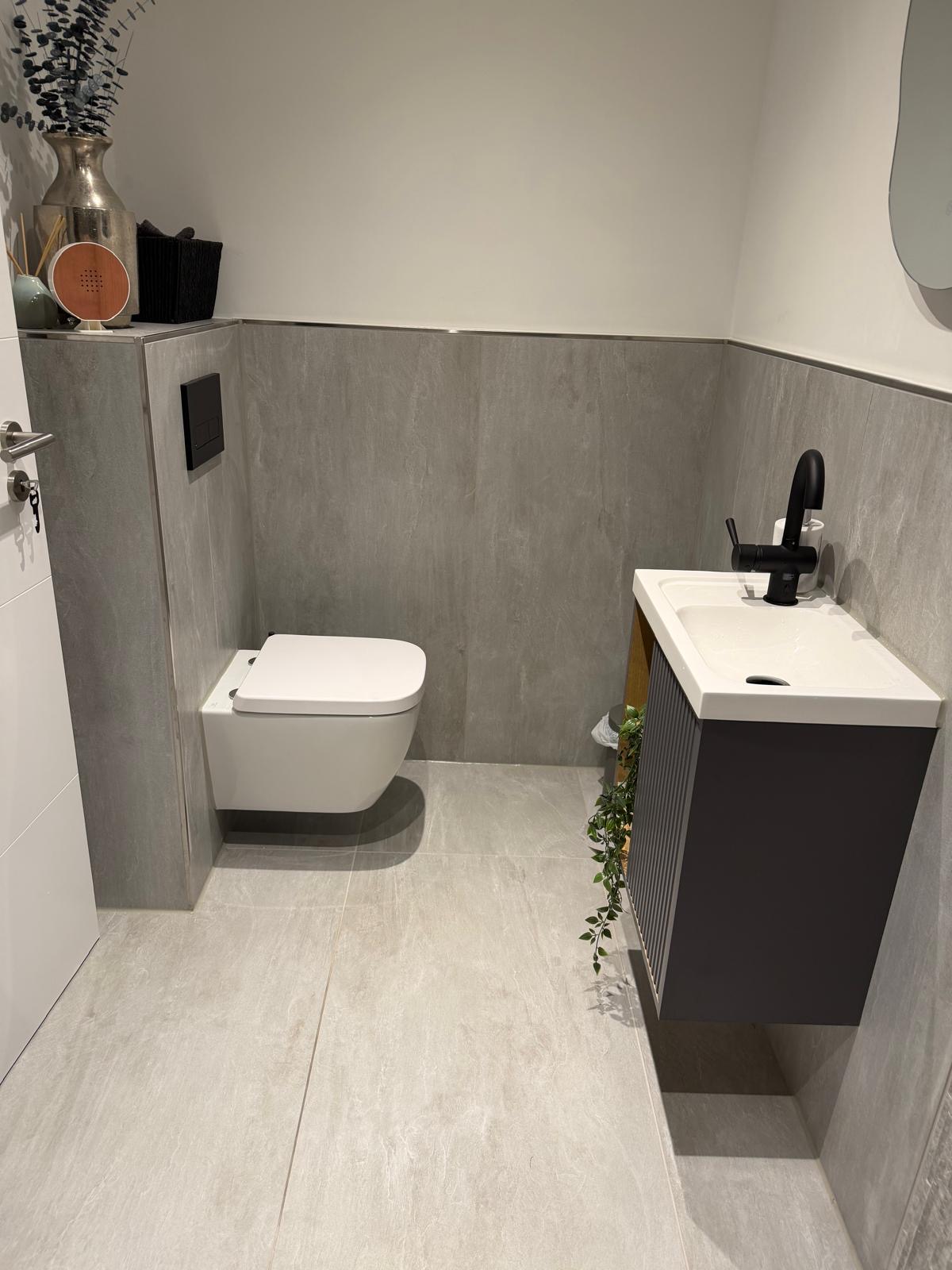 Modernes Gäste-WC mit hellgrauen Fliesen und schwarzen Armaturen