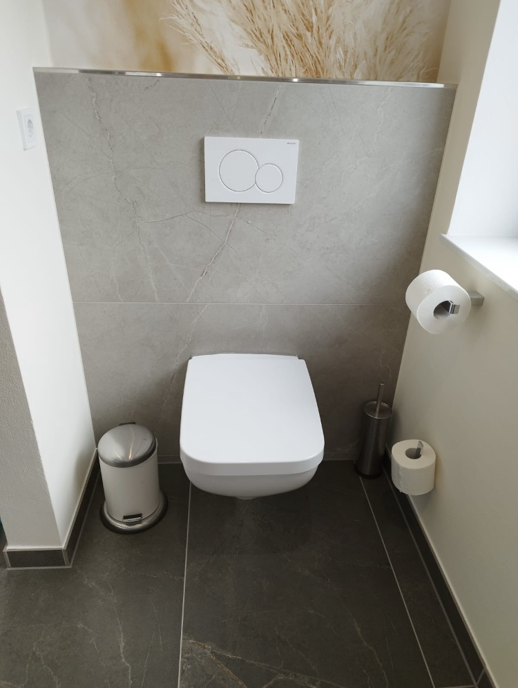 Helles Gäste-WC mit großformatigen grauen Fliesen
