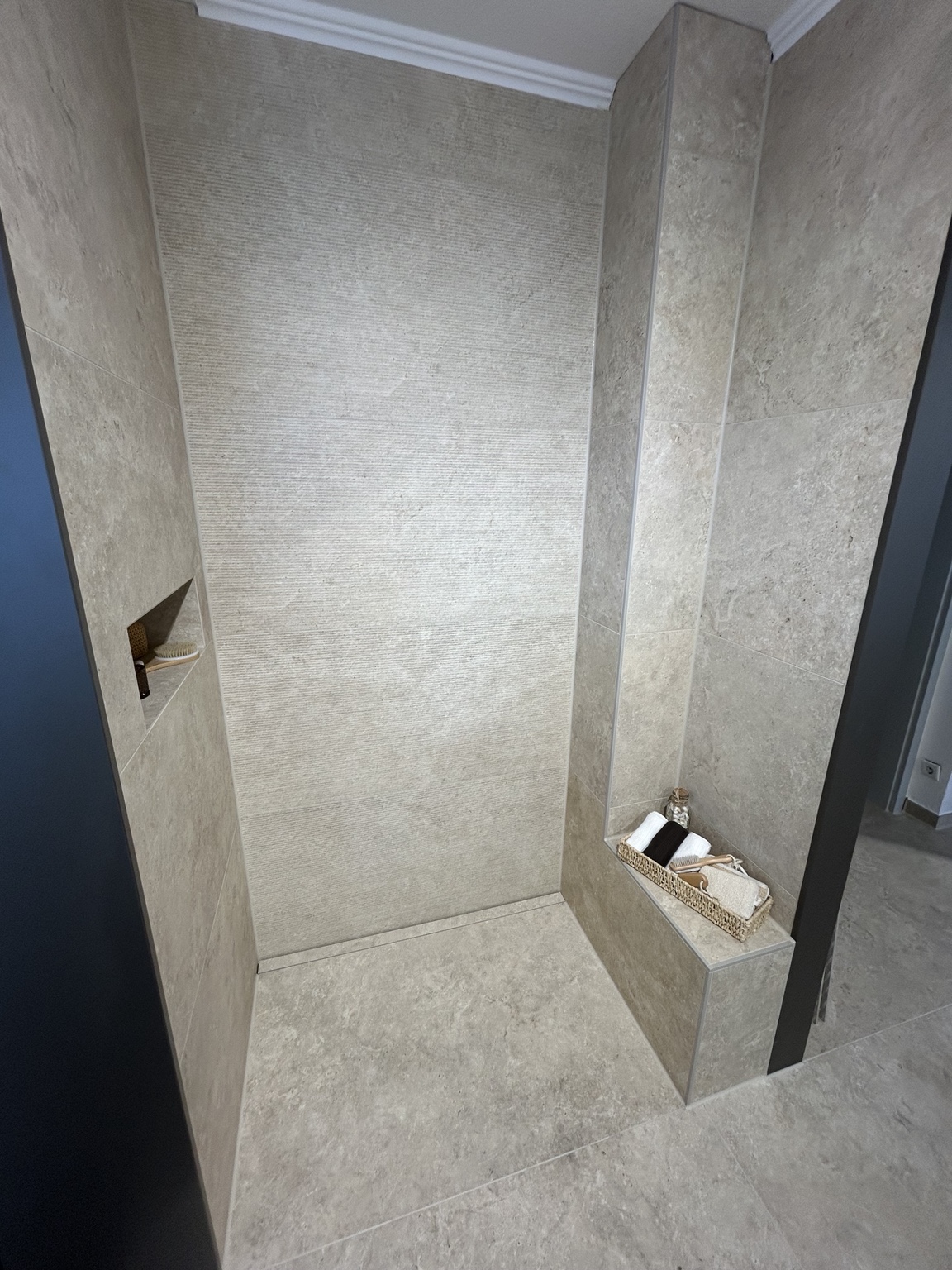 Gewerbliche Ausstellungsdusche mit großformatigen Steinoptik-Fliesen und Sitzbank