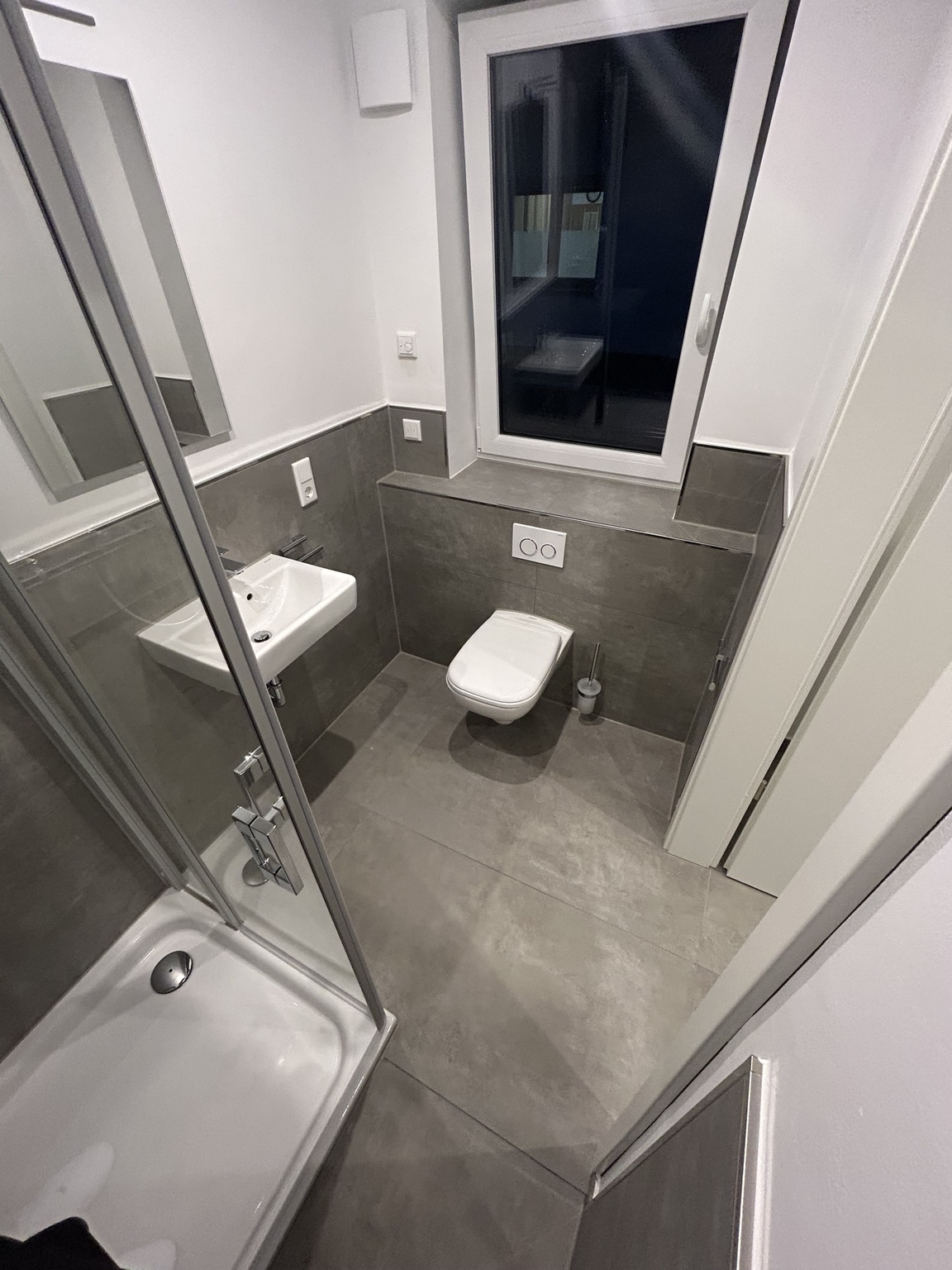 Kompaktes Badezimmer mit grauen Wand- und Bodenfliesen