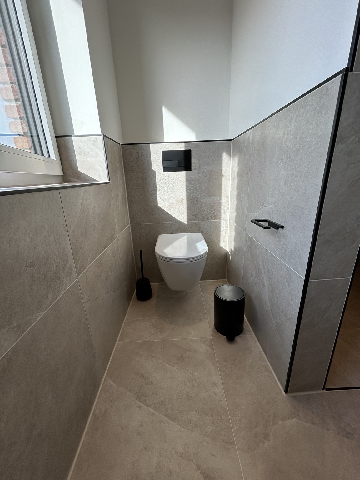 Gäste-WC mit Natursteinoptik-Fliesen und schwarzen Details