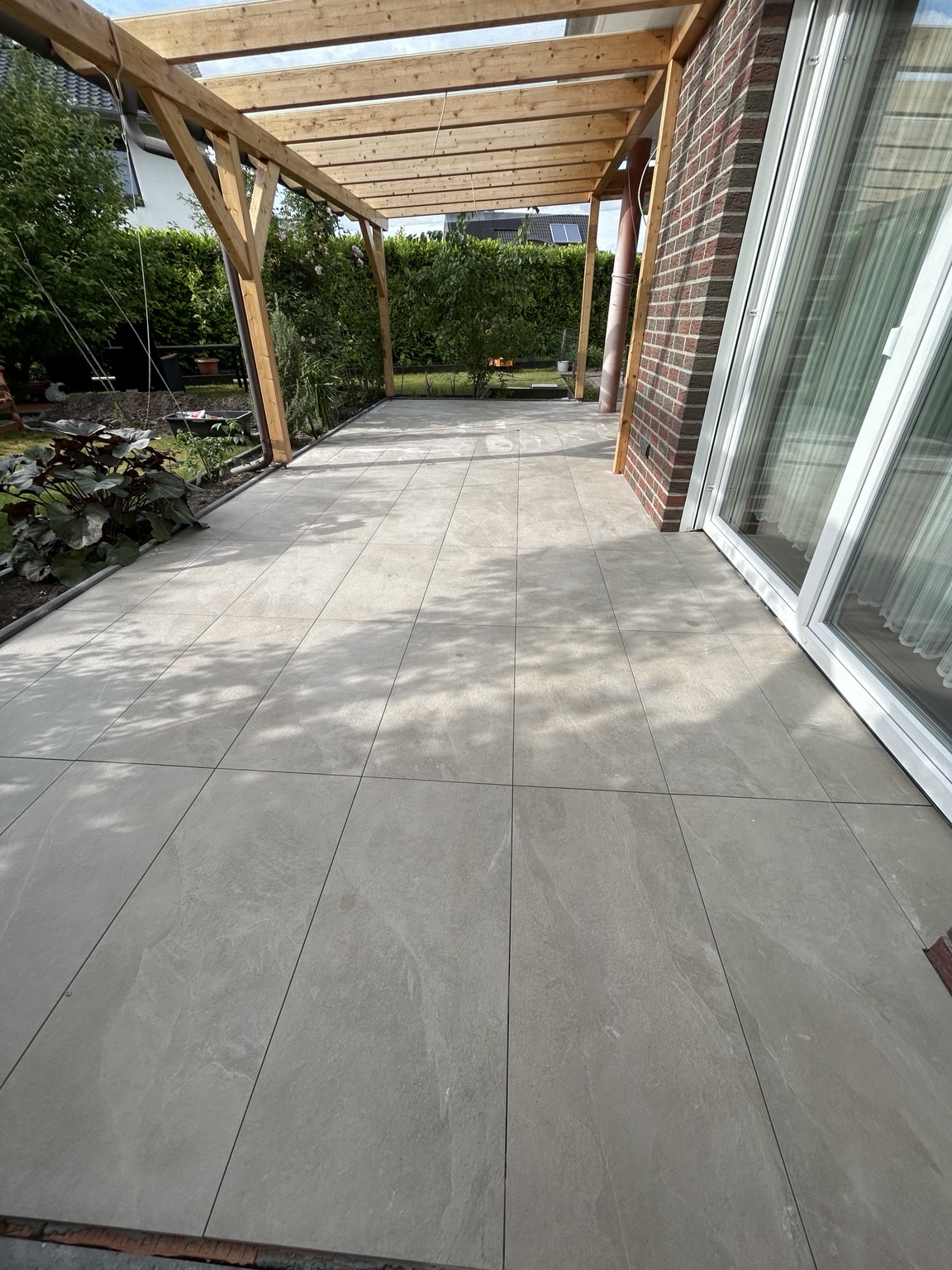 Geflieste Terrasse unter einer Holzkonstruktion