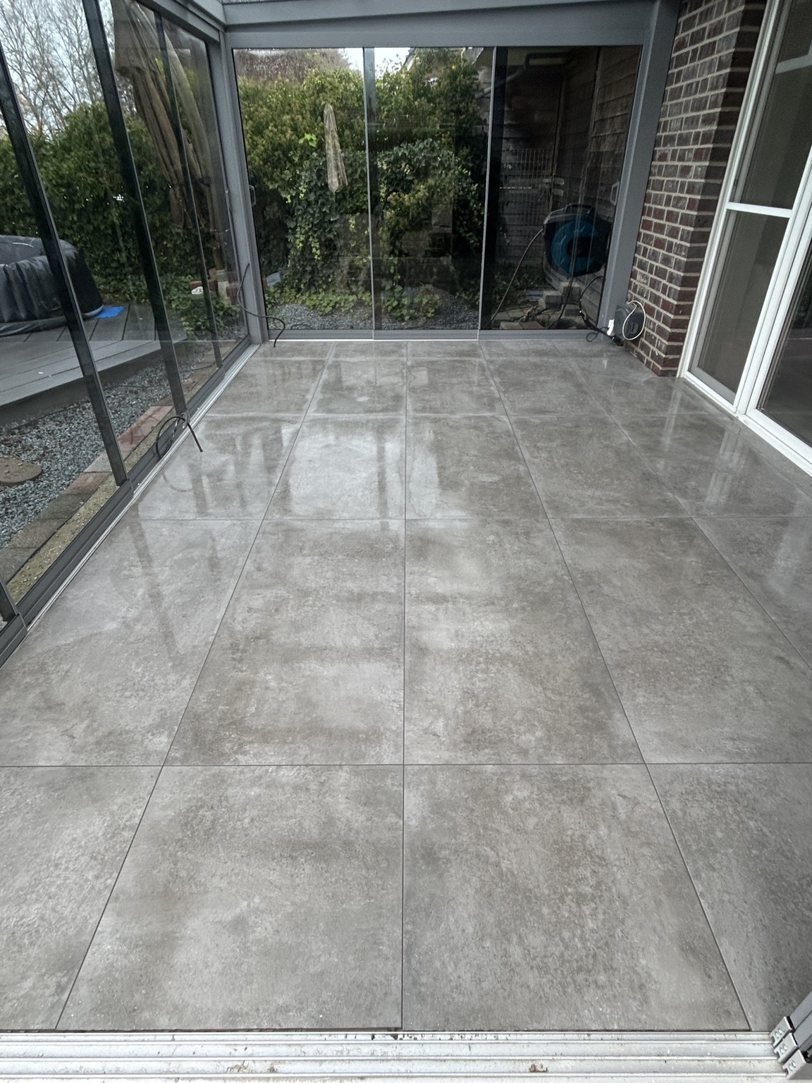 Geschützter Terrassenbereich mit großformatigen grauen Bodenfliesen
